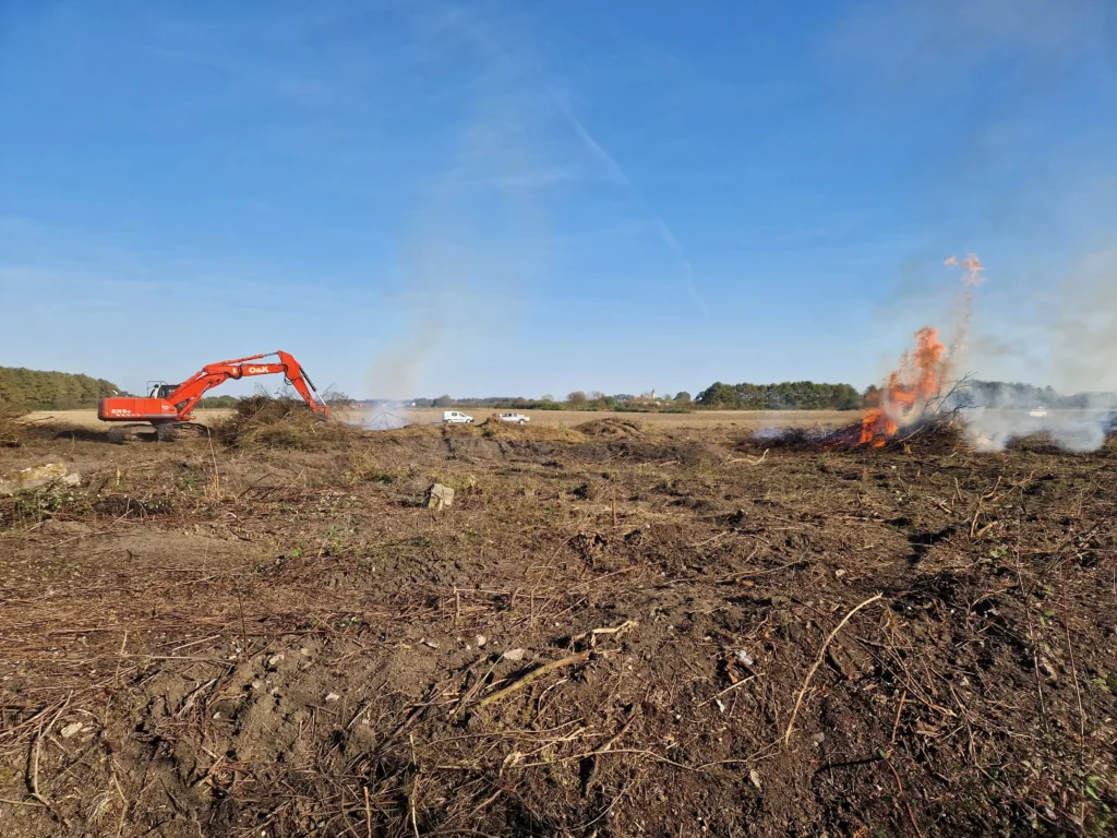Bager čisti polje, dok grane gore u vatri
