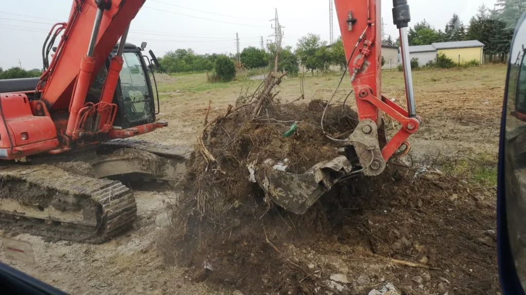 Bager iskopava zemlju i korijenje na gradilištu